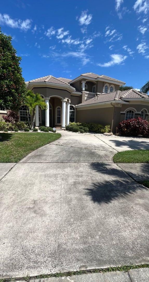 A grey, stained concrete driveway before pressure washing