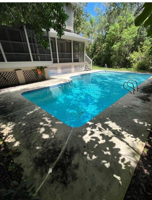A pool deck covered in black mildew and algae before cleaning